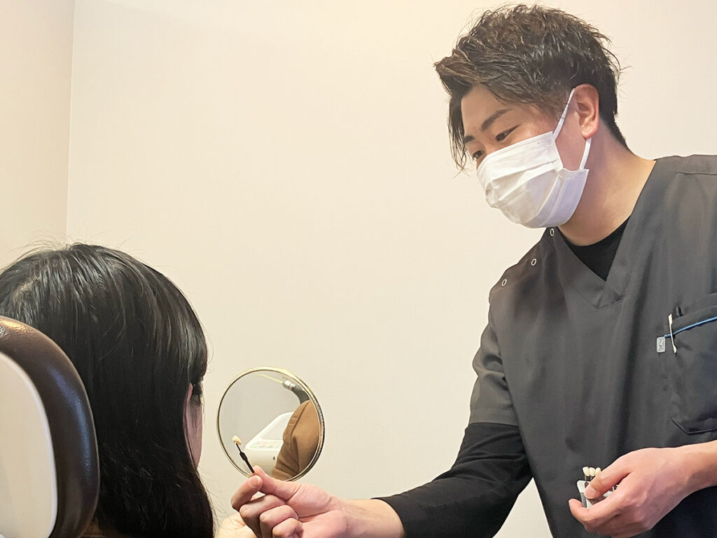 セラミストが前歯のセラミックと天然歯の色を確認する様子
