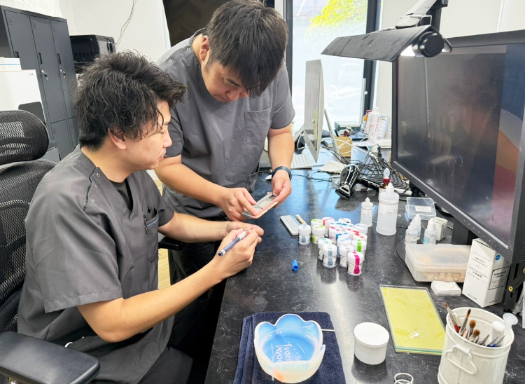 歯科医師とセラミストが前歯のセラミックの色と形を確認する様子