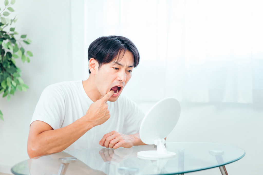 口内の様子を鏡で見る男性